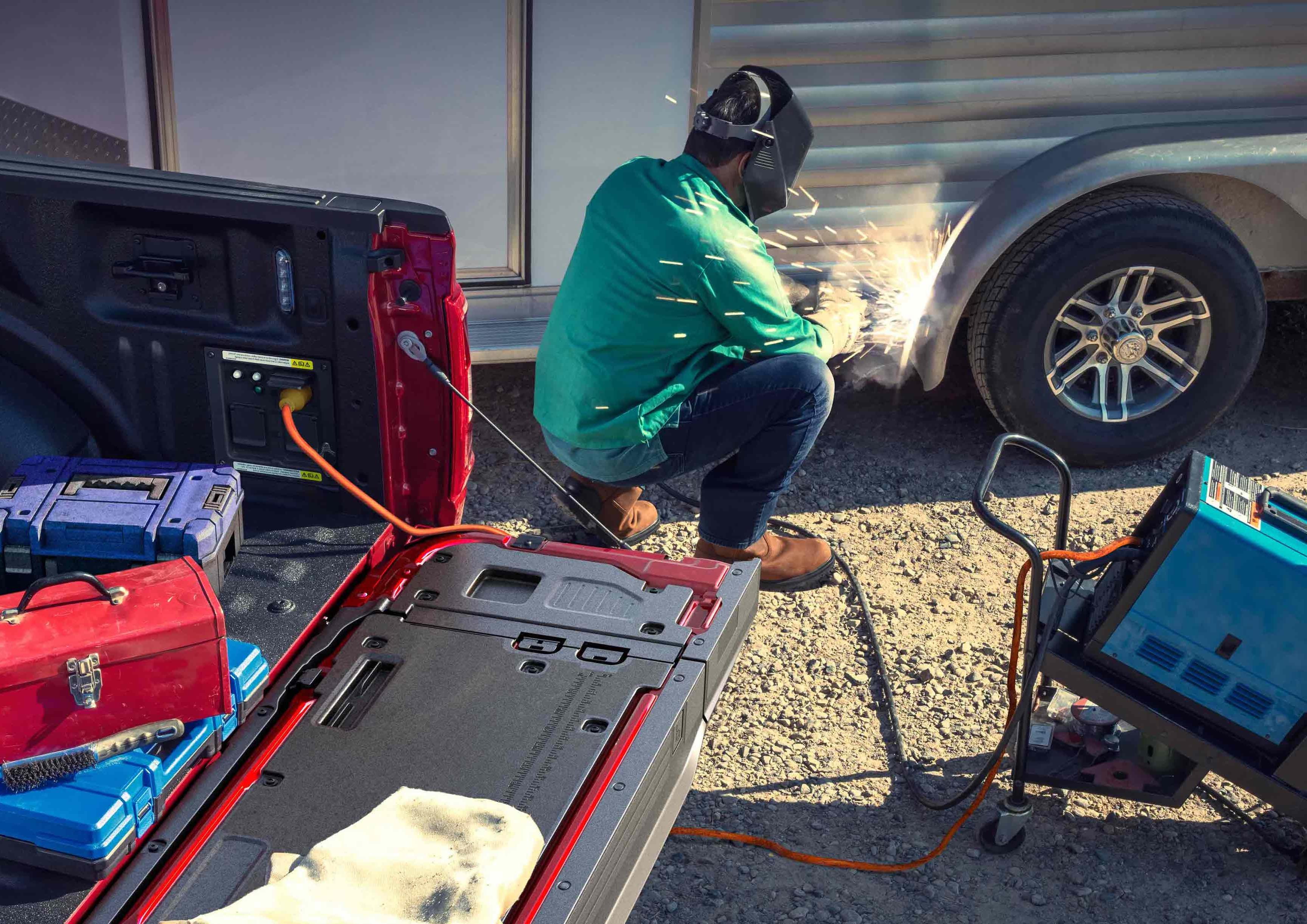 Person using a TIG welder that's plugged into the Pro电源板载 feature located in the truck bed